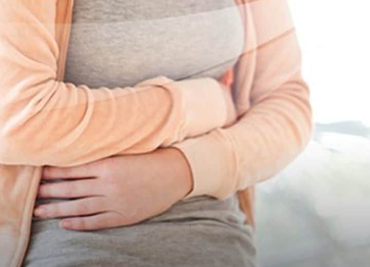 constipated woman grabbing her stomach in pain